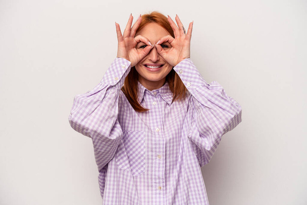 Mujer joven caucásica aislada sobre fondo blanco mostrando signo aceptable sobre los ojos - Foto, Imagen