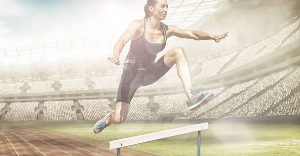 Spots of light against caucasian female athlete jumping over hurdles against sports stadium. sports, fitness and competition concept - Zdjęcie, obraz