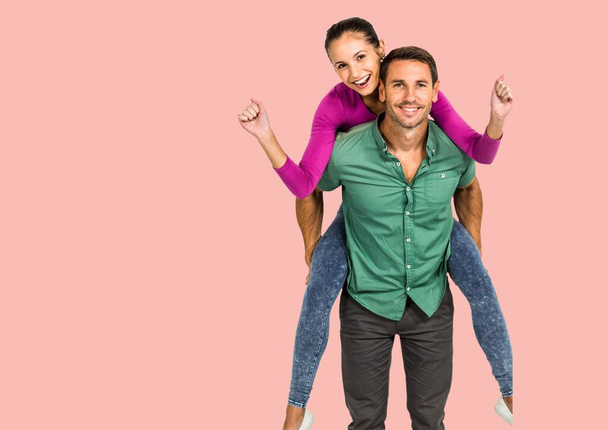 Portrait of caucasian man giving a piggy back ride to his wife against copy space on pink background. love and relationship concept - Foto, Bild