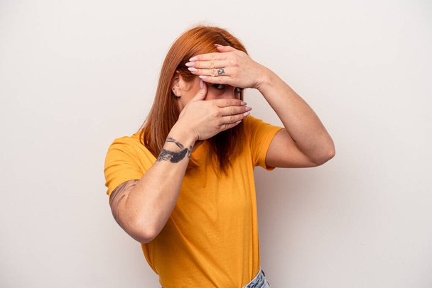 Young caucasian woman isolated on white background blink at the camera through fingers, embarrassed covering face. - Photo, Image