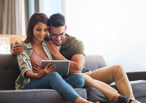 Ligado a um fim-de-semana confortável. Tiro de um jovem casal usando um tablet digital juntos em casa. - Foto, Imagem