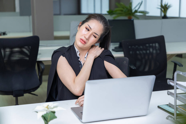 Mature Businesswoman suffering from shoulder pain at workplace. - Photo, Image