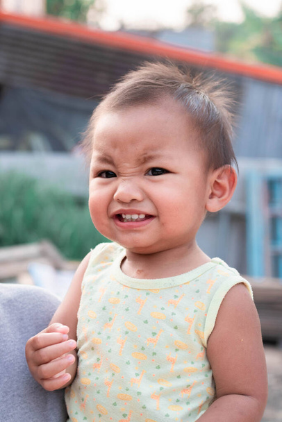 Ένα δίχρονο κορίτσι διασκεδάζει και είναι χαρούμενο και δείχνει τα δόντια του μωρού της. - Φωτογραφία, εικόνα