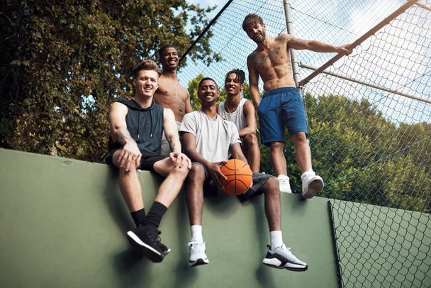 Мы чувствуем себя как дома на корте. Портрет группы спортивных юношей, болтающихся на баскетбольной площадке. - Фото, изображение