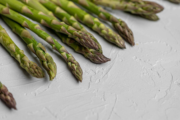 On a gray decorative background, close-up of the tops of fresh green asparagus - Foto, Bild