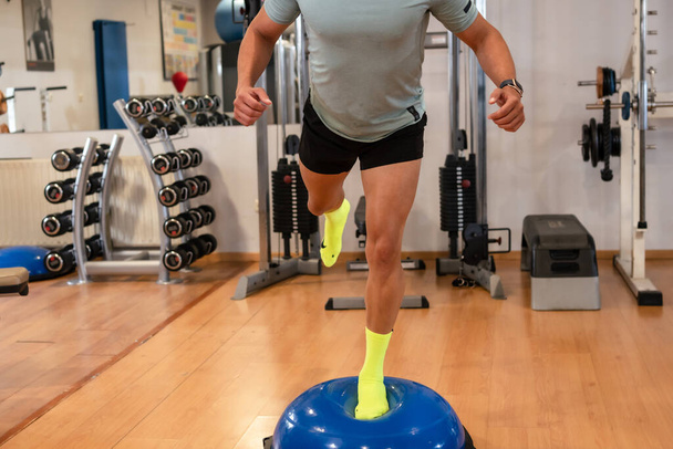 Spor salonunda lastik bir kürede ayak bileği egzersizi yapan beyaz bir adamın portresi. Spor yapan sağlıklı ve sağlıklı bir hayat. - Fotoğraf, Görsel