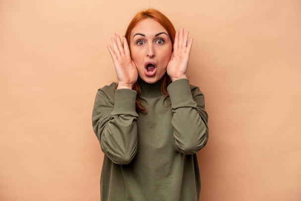 Young caucasian woman isolated on beige background surprised and shocked. - Foto, Imagem
