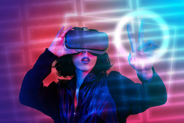 La joven está utilizando visor de realidad virtual. Retrato de mujer moderna con aspecto moderno y colores brillantes. - Foto, imagen