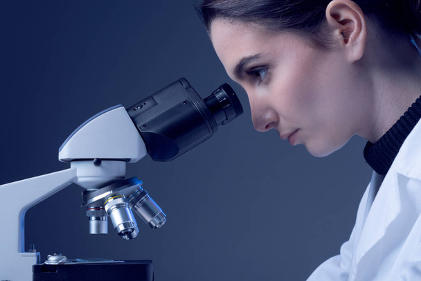 Young researcher looking through a microscope and checking samples, medical research concept - Фото, зображення