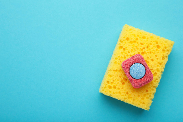 Dishwasher tablet on a dishwashing sponge on a blue background, dishwashing products. Top view - Foto, afbeelding