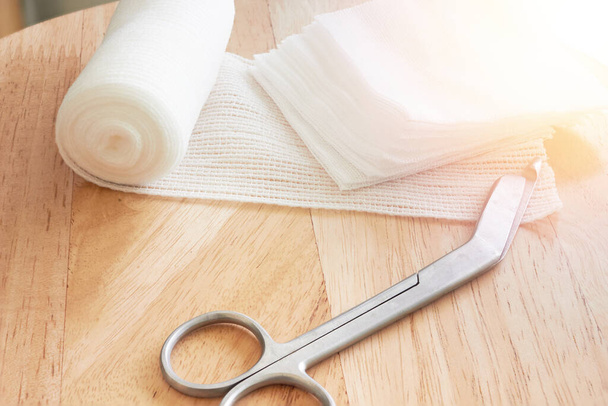 Dressing or clean wound tools includes Roll gauze,pile of gauzes and gauze roll cutter or scissors with sun flare - Photo, Image