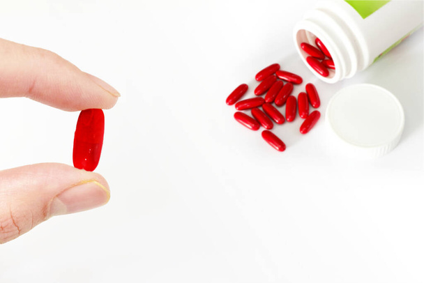 doigt tenir médicament pilule rouge avec bouteille - Photo, image