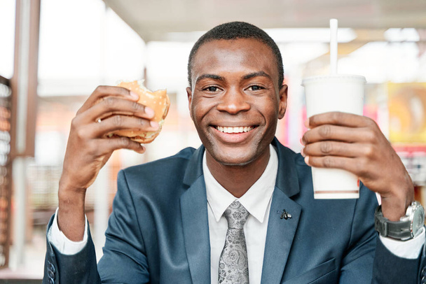uomo che mostra hamburger e bevande analcoliche - Foto, immagini