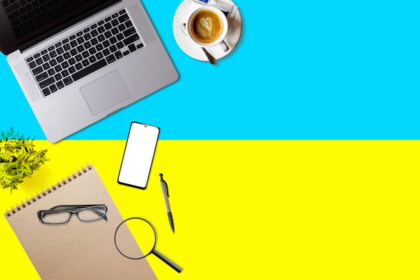 Visit Ukraine concept for your web banner or print materials. Top view of a laptop, coffee cup on Ukraine national flag. Flat style travel planninng website header. - Photo, Image