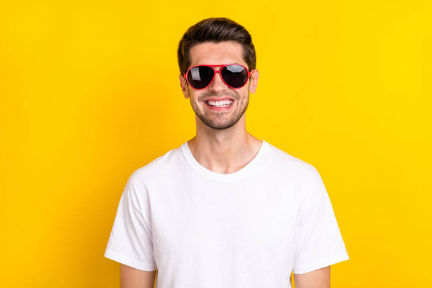 Photo of funky millennial brunet guy wear glasses t-shirt isolated on yellow color background - 写真・画像