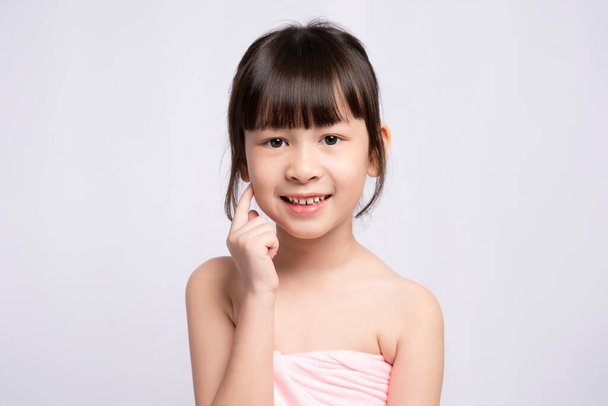 Menina asiática, rosto brilhante no fundo branco, conceito de tratamentos de beleza de cuidados com a pele. Modelo branco com pele de cara limpa e saudável. rosto da menina - Foto, Imagem