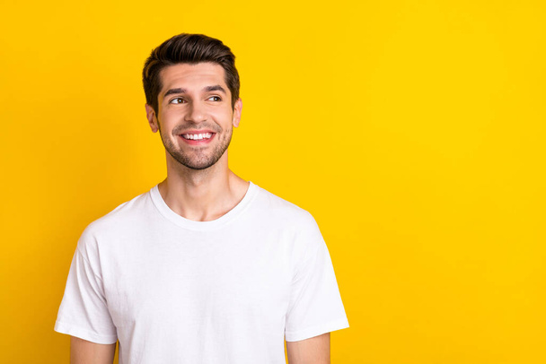 Photo of interested smart minded nice man look empty space wear white t-shirt isolated yellow color background - Foto, Bild