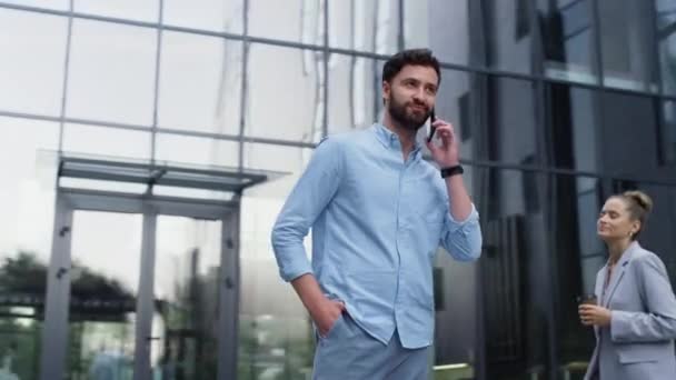 Hezký muž u telefonu ve skleněné kancelářské budově. Moderní firemní oblast - Záběry, video