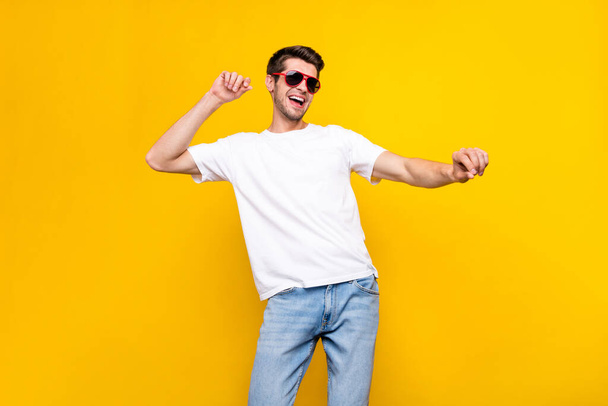 Photo de cool jeune brunet mec danse porter lunettes t-shirt isolé sur fond de couleur jaune - Photo, image