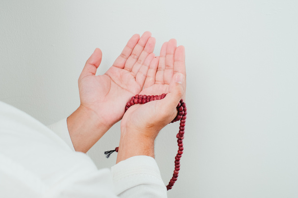Chiudi Mano tenendo un tasbih o perline di preghiera su sfondo bianco - Foto, immagini
