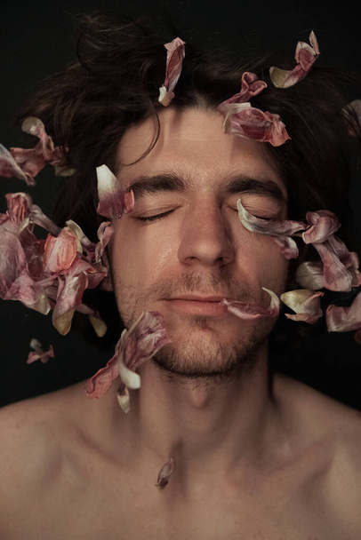 το πρόσωπο ενός ανθρώπου στον οποίο πετούσαν τα πέταλα των λουλουδιών - Φωτογραφία, εικόνα
