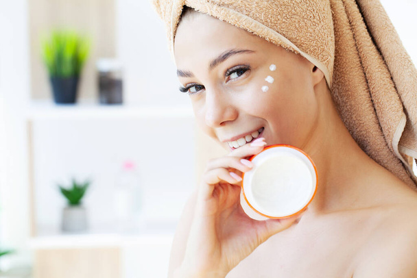 Beautiful woman applying moisturizer cream on her face. - Φωτογραφία, εικόνα