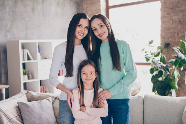 Photo of three cheerful ladies hug relatives good mood motherhood siblings living-room school girl indoors - Zdjęcie, obraz