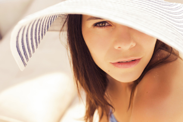 Όμορφη μελαχρινή γυναίκα στην παραλία μόνο χαλαρώνοντας σε ένα καπέλο. S - Φωτογραφία, εικόνα