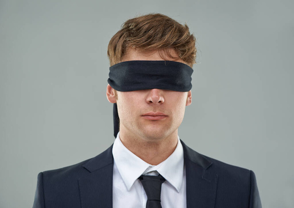 Going blindly into the deal.... Cropped view of a young businessman with his eyes blindfolded. - Foto, Imagem