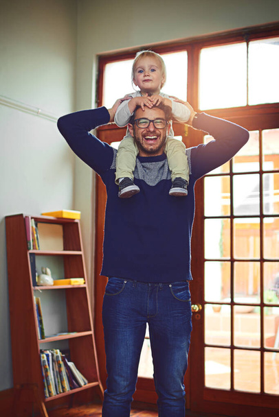 Boys day at home is gonna be so fun. Portrait of a father carrying his little son on his shoulders at home. - Foto, Imagem