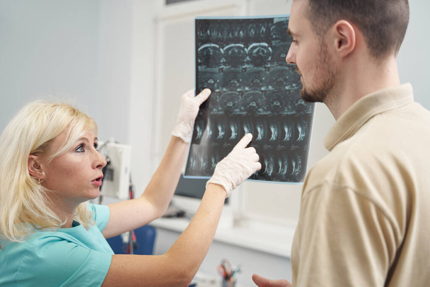 Женщина-врач показала молодому человеку рентген позвоночника - Фото, изображение