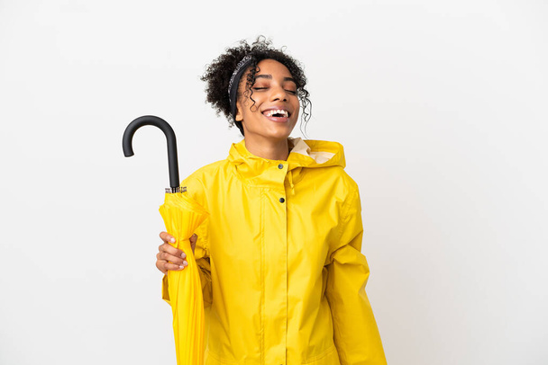 Young woman with rainproof coat and umbrella isolated on white background laughing - Photo, Image
