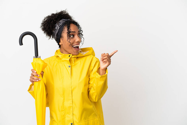 Giovane donna con impermeabile e ombrello isolato su sfondo bianco che intende realizzare la soluzione alzando un dito - Foto, immagini