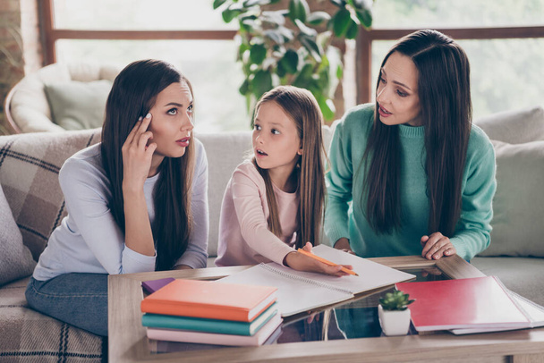 Photo of mommy with siblings sitting divan apartment help with lesson homework minded thoughtful indoors - Фото, изображение