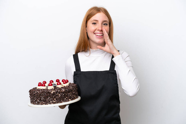 Fiatal vörös hajú nő gazdaság születésnapi torta elszigetelt fehér háttér kiabál száj széles nyitott - Fotó, kép