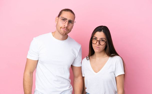 Fiatal fehér pár elszigetelt rózsaszín háttér szemüveggel - Fotó, kép