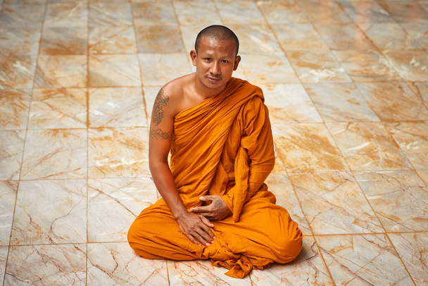 静かな瞑想に座っている。僧院の床に座る僧侶の肖像画. - 写真・画像