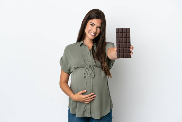 Młoda Brazylijka odizolowana na białym tle w ciąży i trzymająca czekoladę - Zdjęcie, obraz