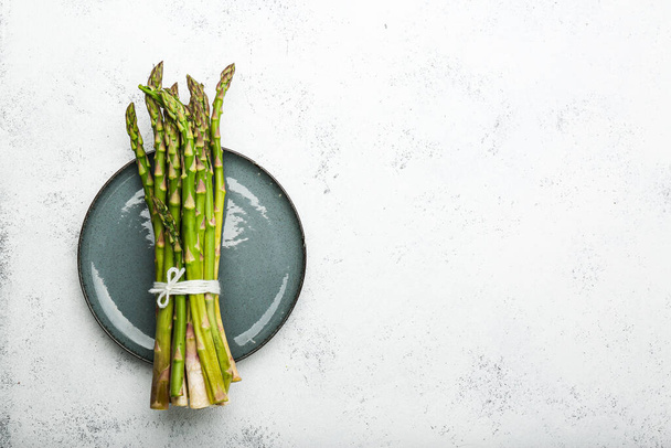 Fresh green asparagus in gray bowl top view. - Foto, afbeelding