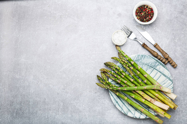 Bunch of fresh green asparagus on a plate with seasonings. Top view, copy space - Fotó, kép