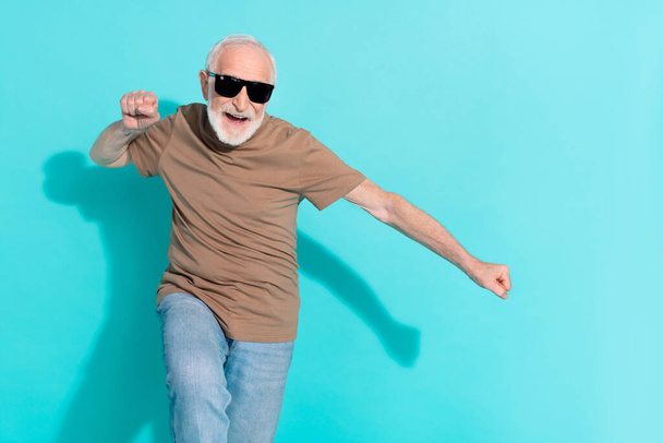 Portrait of attractive cheerful grey-haired man dancing having fun rest isolated over bright blue color background - Фото, изображение