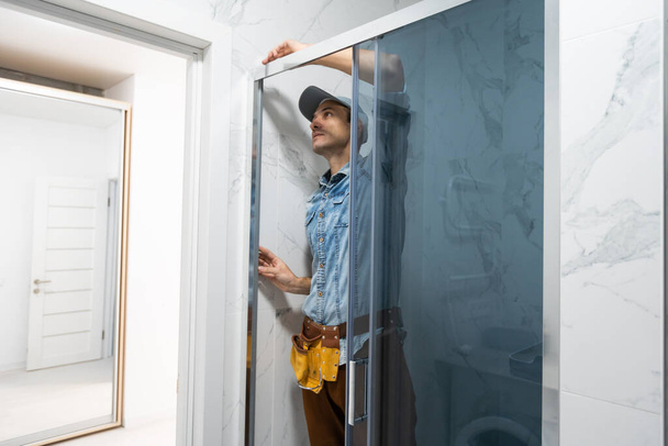 Workers are installing glass door of the shower enclosure. - Foto, immagini