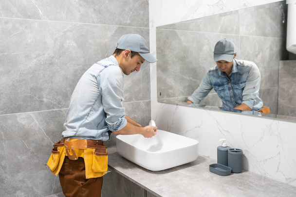 A man is setting the washbasin over the cabinet in the bathroom - Φωτογραφία, εικόνα