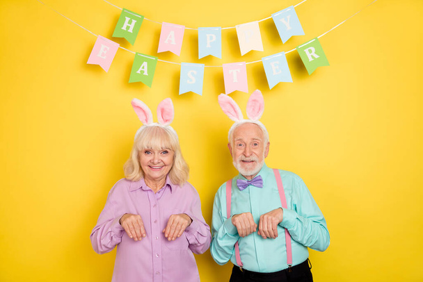Portrait of two attractive trendy cheery funny grey-haired spouses easter having fun isolated over bright yellow color background - Foto, Imagen