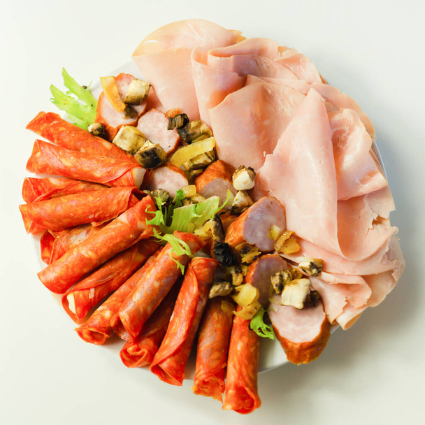 Холодная тарелка, приготовленная для вечеринки с нарезанным чоризо, ветчиной и сосисками, набор мясных закусок - Фото, изображение