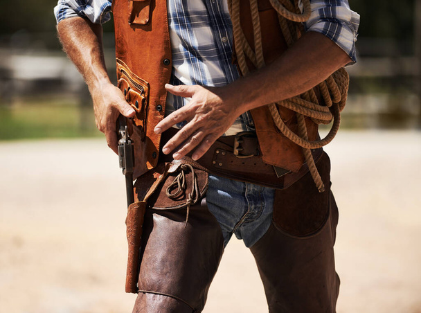 Ready to blow you away. Cropped shot of an unrecognizable cowboy drawing his gun. - Photo, Image