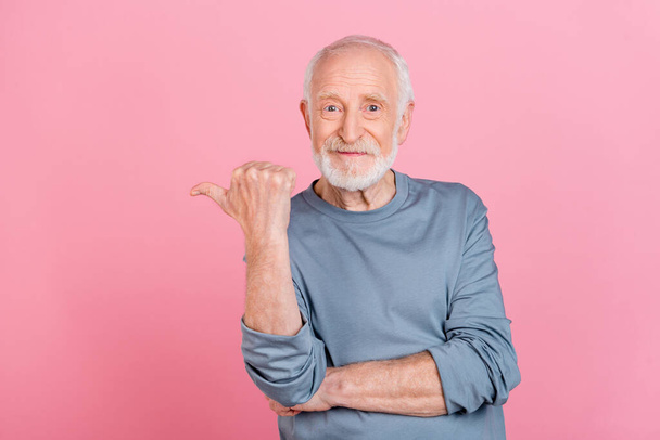Photo of funny sweet retired man grey sweater smiling pointing thumb empty space isolated pink color background - Foto, Imagem