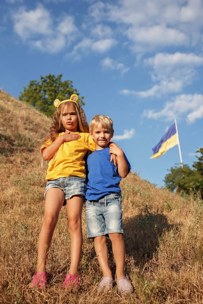 Girl in yellow and boy in blue near biggest national flag of Ukraine. Pray for peace and victory - Photo, Image