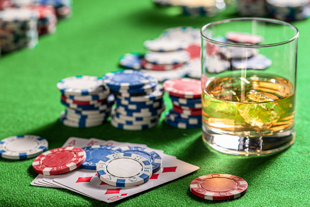 Green gambling table with cards, chips and shiksy. Poker table with cards, chips and a glass of whiskey with ice. - Foto, imagen