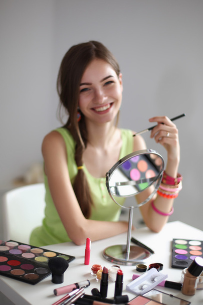Young beautiful woman making make-up near mirror, isolated on grey background - Fotoğraf, Görsel